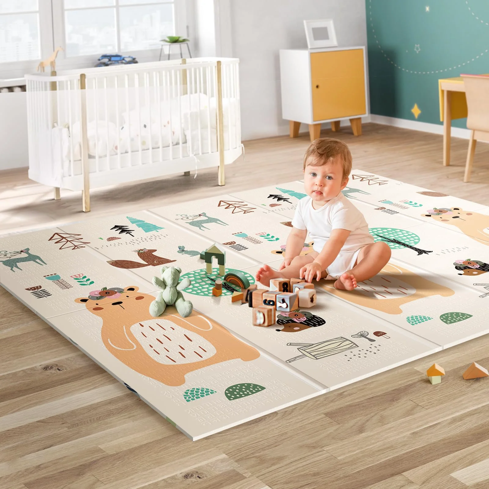 A baby sitting on a bear play mat in a bright living room